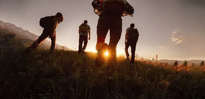 Silhouettes of four young hikers with backpacks